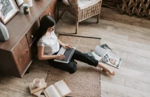 žena sedi na podu i gleda u laptop